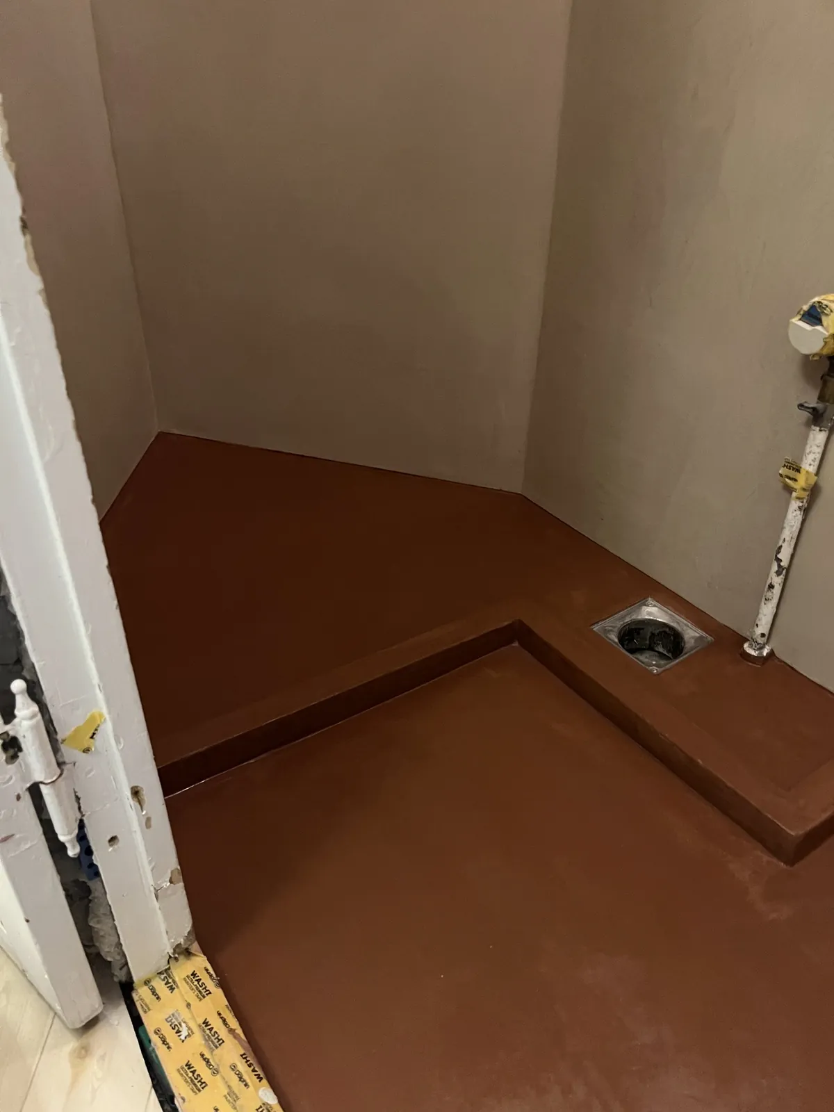 Brunt microcementgulv i lille rum med gulvafløb – Maler Microcement, Herlev og omegn