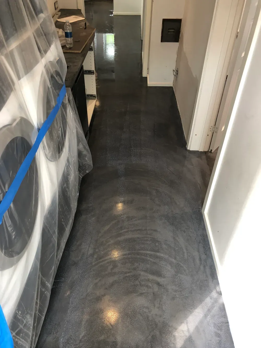 Mørkt microcementgulv i gang og entre, afdækket under arbejdet – Maler Microcement, Herlev og omegn