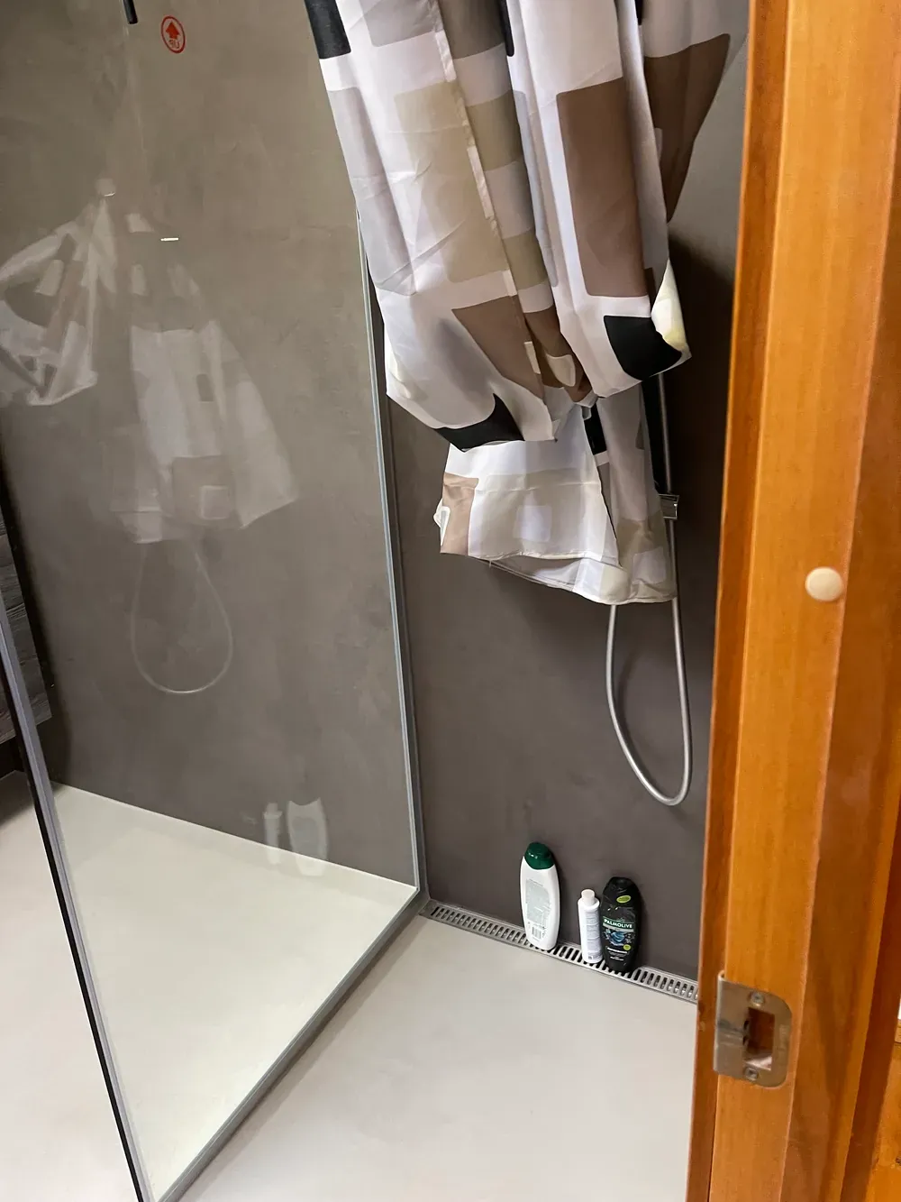 Badeværelse med grå microcementvæg og lyst gulv i brusenichen – Maler Microcement, Herlev og omegn