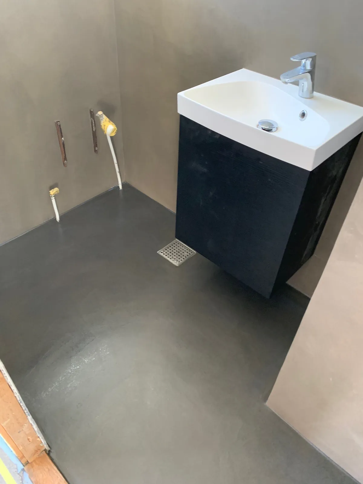 Sort gulv og håndvask på sort møbel set fra siden – Maler Microcement, Herlev og omegn