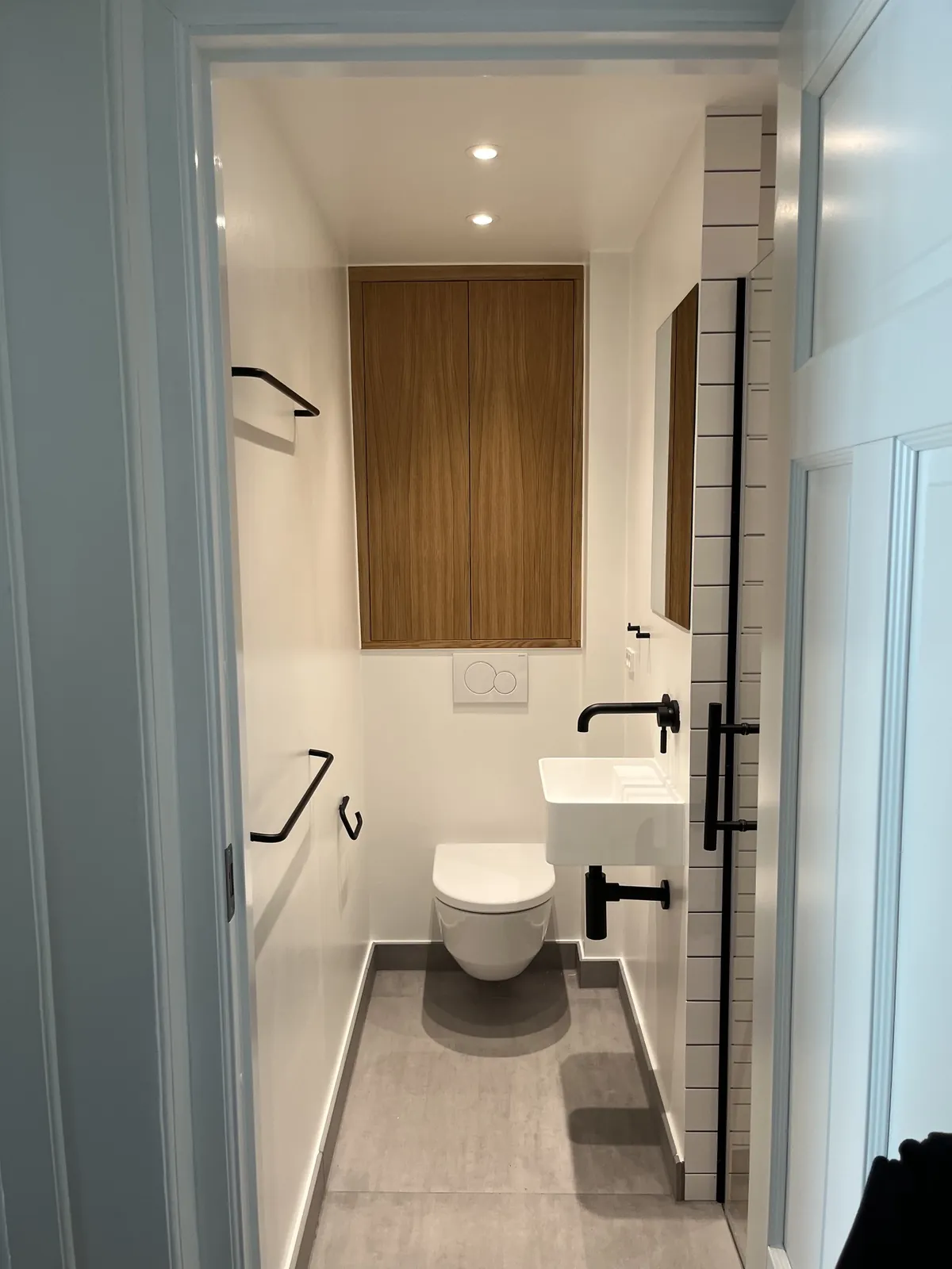 Toilet med hvide fliser og sort armatur set fra døren – Maler Microcement, Herlev og omegn